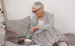 A woman uses a laptop. She is ready to begin online therapy in San Diego, CA with Headway Therapy. 