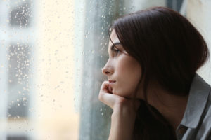 A woman is looking out of the window. This demonstrates concepts of therapy in San Diego, CA. Our therapists in San Diego, CA can provide therapy for women in San Diego, CA and online therapy in California.