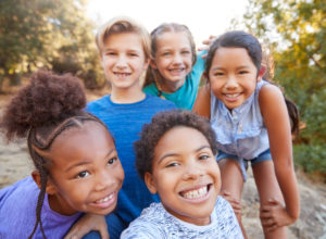 A group of children is smiling. They are feeling happy since starting child therapy in San Diego, CA and online therapy for children in California.