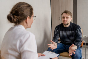 A man sits in with a healthcare provider. This represents concepts of trauma therapy in San Diego, CA. Headway predominantly provides online therapy for women in California. This often includes online pregnancy counseling in California.